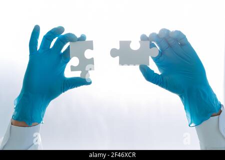 doctor in protective gloves is connecting the pieces of the puzzle. Stock Photo