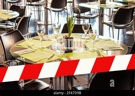 Glasses, flower, fork, knife served for dinner in restaurant with cozy interior. Stock Photo