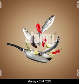 Creative concept with a grill pan, fresh seabass fishes and vegetables. Minimalistic creative food concept. Stock Photo