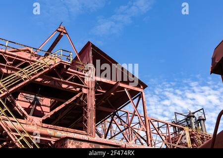 Abandoned industrial site, stairs and open walkways with rusted metal and peeling paint against a beautiful blue sky, horizontal aspect Stock Photo