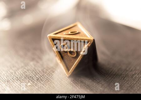 High contrast close-up image of a 8-sided role playing die surrounded by smoke. Stock Photo