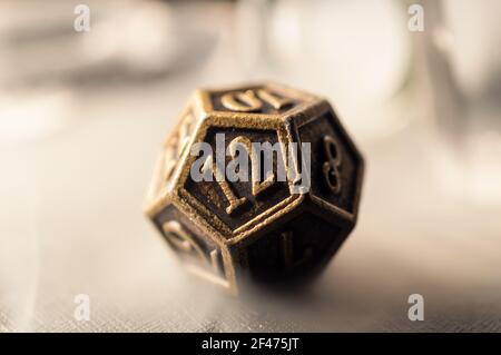 High contrast close-up image of a 12-sided role playing die surrounded by smoke. Stock Photo