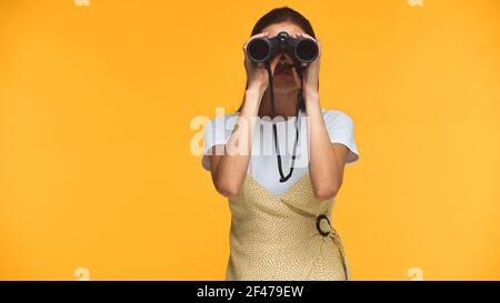 woman looking through binoculars isolated on yellow Stock Photo