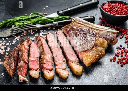 Grilled cowboy or ribeye beef steak with herbs and spices. Black background. Top view Stock Photo