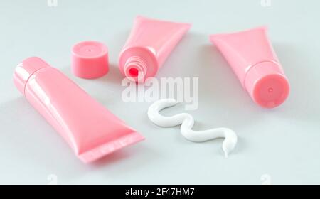Blank plastic tubes with squeezed out white beauty or medical cream Stock Photo