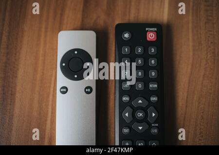 A top view shot of two different remote controls of  TV on a wooden background. Stock Photo