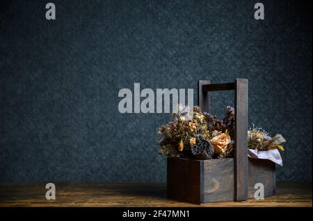 Composition of dried flowers in a wooden basket on dark background Stock Photo