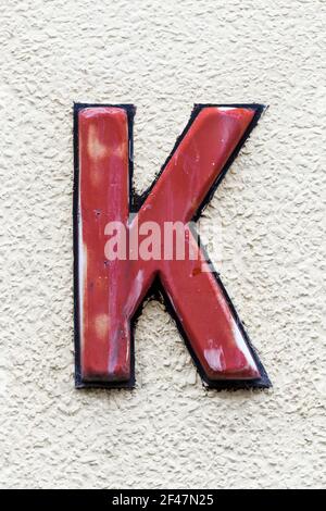 Weathered letter K in red plastic Stock Photo