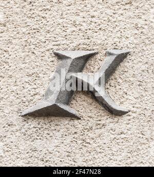 Capital letter K on roughly plastered wall Stock Photo