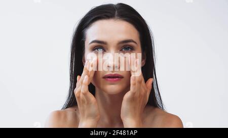 pretty woman applying face cream while looking at camera isolated on white Stock Photo