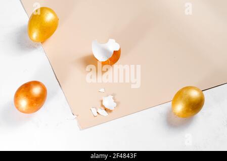 Scattered gold eggs, shell on pastel beige background. Concept of easter, priceless ideas, business investment, or breakfast Stock Photo