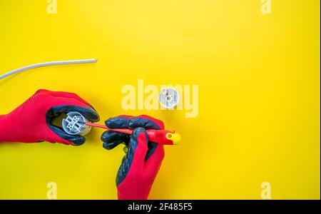 Electrician peeling off insulation from wires - closeup on hands and pliers Stock Photo