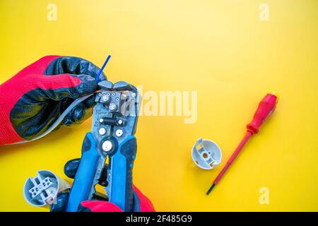 Electrician peeling off insulation from wires - closeup on hands and pliers Stock Photo