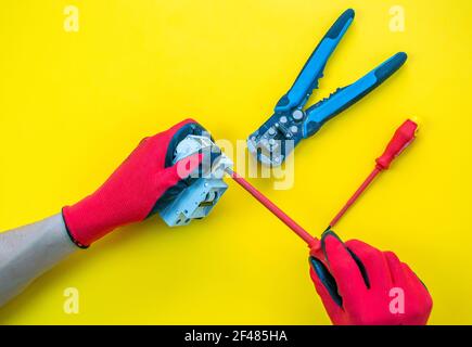 Electrician peeling off insulation from wires - closeup on hands and pliers Stock Photo