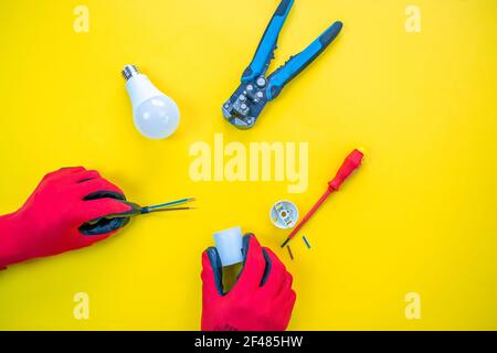 Electrician peeling off insulation from wires - closeup on hands and pliers Stock Photo