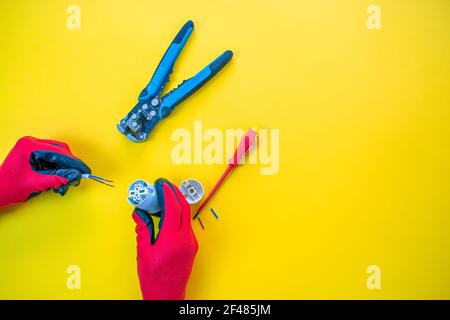 Electrician peeling off insulation from wires - closeup on hands and pliers Stock Photo