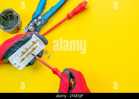 Electrician peeling off insulation from wires - closeup on hands and pliers Stock Photo