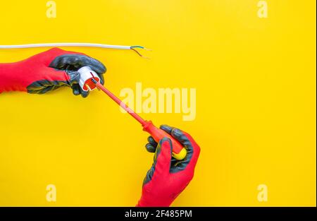 Electrician peeling off insulation from wires - closeup on hands and pliers Stock Photo