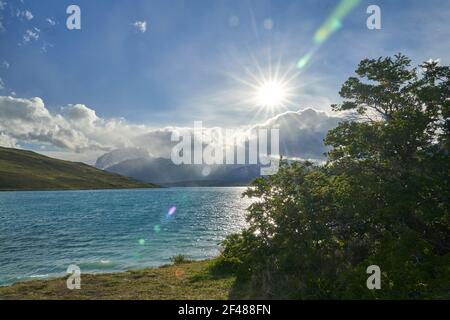 Towers of torres del Paine national park covered in clouds with dark green forest a lake and snow covered mountains of the Andes in Patagonia southern Stock Photo