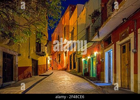 Colourful colonial era houses with balconies in alley paved with square cut stones at night in the city Guanajuato, Central Mexico Stock Photo