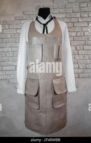 Gray leather apron for staff on a mannequin, on a gray background. Uniform. Stock Photo
