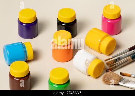 artistic brushes for painting in pot with gouache paints blurred in the background Stock Photo