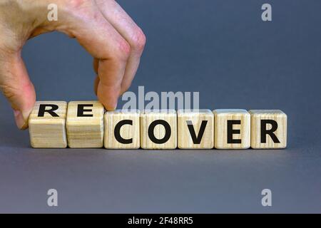 Time to recover symbol. Businessman turns wooden cubes and changes the word 'cover' to 'recover'. Beautiful grey background. Business, cover or recove Stock Photo