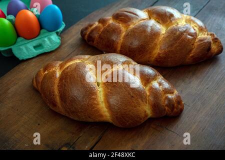 Easter sweet bread and colorful eggs, tsoureki cozonac loaf on wood table background, Festive traditional religion dessert, braided brioche Stock Photo