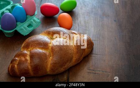 Sweet bread and colorful easter eggs, tsoureki cozonac loaf on wood table background, Easter greeting card template. Festive traditional religion dess Stock Photo