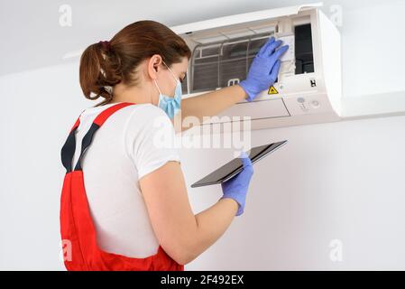 Female technician using digital tablet and repairing air conditioner Stock Photo