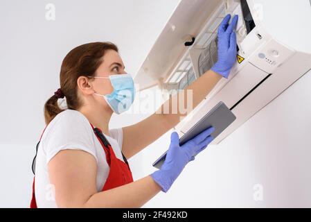 Female technician using digital tablet and repairing air conditioner Stock Photo