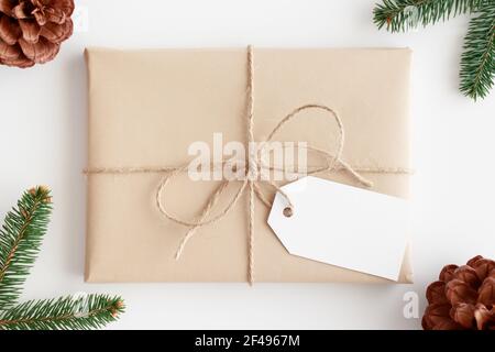 Top view of a kraft christmas gift with a blank tag surrounded with pine cones and leaves. Stock Photo