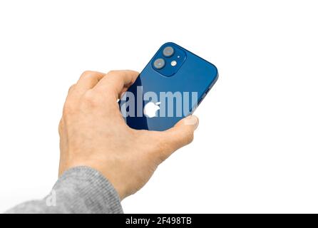 Kharkov, Ukraine - March 12, 2021: Man holds Apple iPhone 12 with backside on white isolated background Stock Photo