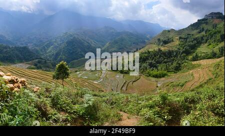 Wide panoramic view of rice terraces in the mountains near Sa Pa. Clouds over mountain range. Vietnam. Stock Photo