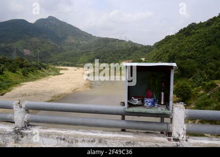 Religious box with incense sticks along a road on a bridge on background of mountains. Vietnam Stock Photo