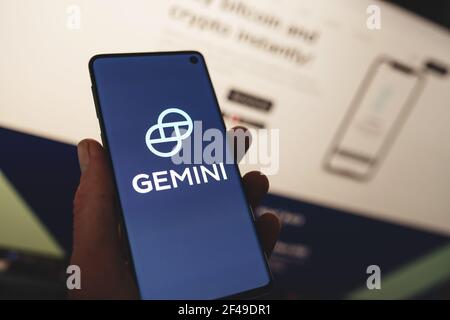 Man holding a smartphone with Gemini app logo with blurred website background. Cryptocurrency exchange, wallet platform Stock Photo
