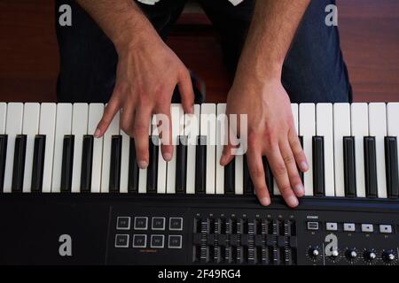 A closeup top view of male musician hands playing on electronic piano keyboard in a studio Stock Photo