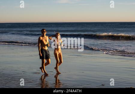 Malibu, CA USA - March 1st, 2021: Close up view of a young couple holding a drink and walking on El Matador Beach Stock Photo