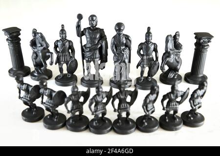 Black metal chess pieces on chessboard with pawns in front of castles knights centurions king and queen on white background Stock Photo