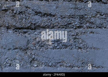Cracked and crumbling concrete and stone aggregate wall texture painted dark gray, horizontal aspect Stock Photo