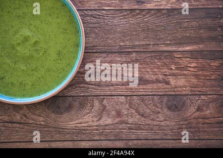 Fresh vegetable detox soup made from peas in a plate on brown wooden table, top view with space for text. Tasty Stock Photo
