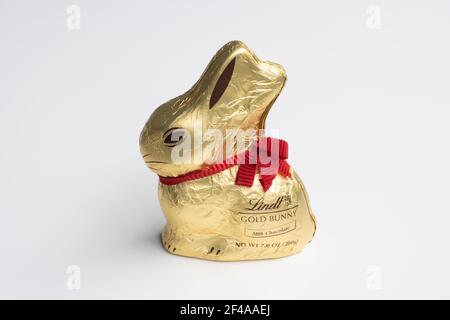 Lindt Gold Bunny isolated on a white background. Milk chocolate Easter bunny wrapped in golden foil with a red ribbon, produced by Lindt, a Swiss ... Stock Photo
