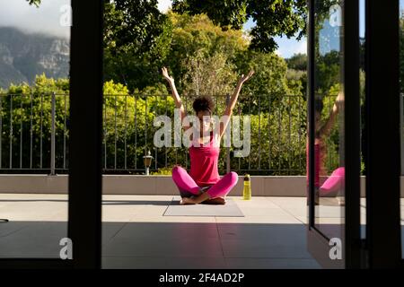 Mixed race woman exercising practicing yoga on a terrace Stock Photo