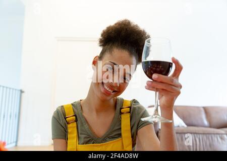 Mixed race woman drinking a glass of wine and smiling at home Stock Photo