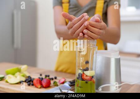 Mixed race woman making a healthy drink and smiling in a kitchen Stock Photo