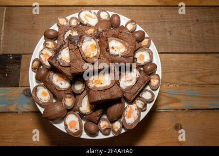 A plate of delicious chocolate cream easter egg brownies, chocolate easter eggs treats on a wooden kitchen table Stock Photo
