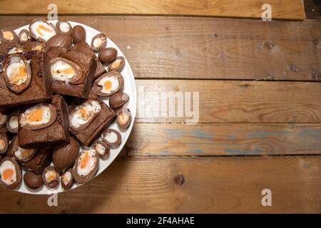 A plate of delicious chocolate cream easter egg brownies, chocolate easter eggs treats on a wooden kitchen table Stock Photo
