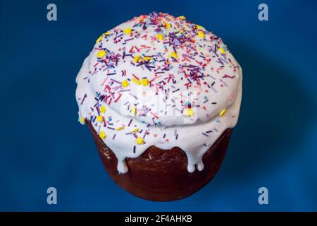 Easter holidays isolated sweet bread, paska decorated with sugar icing on blue background. Orthodox handmade kulich dessert with topping. Spring holid Stock Photo