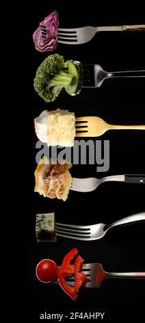 Different food impaled on forks against dark background Stock Photo