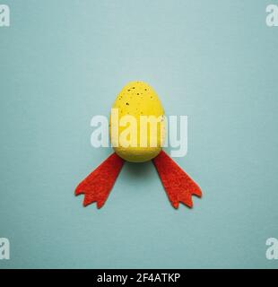 Easter chick made of yellow Easter egg and cotton chicken legs. Minimal nature background. Spring holidays concept. Flat lay Stock Photo